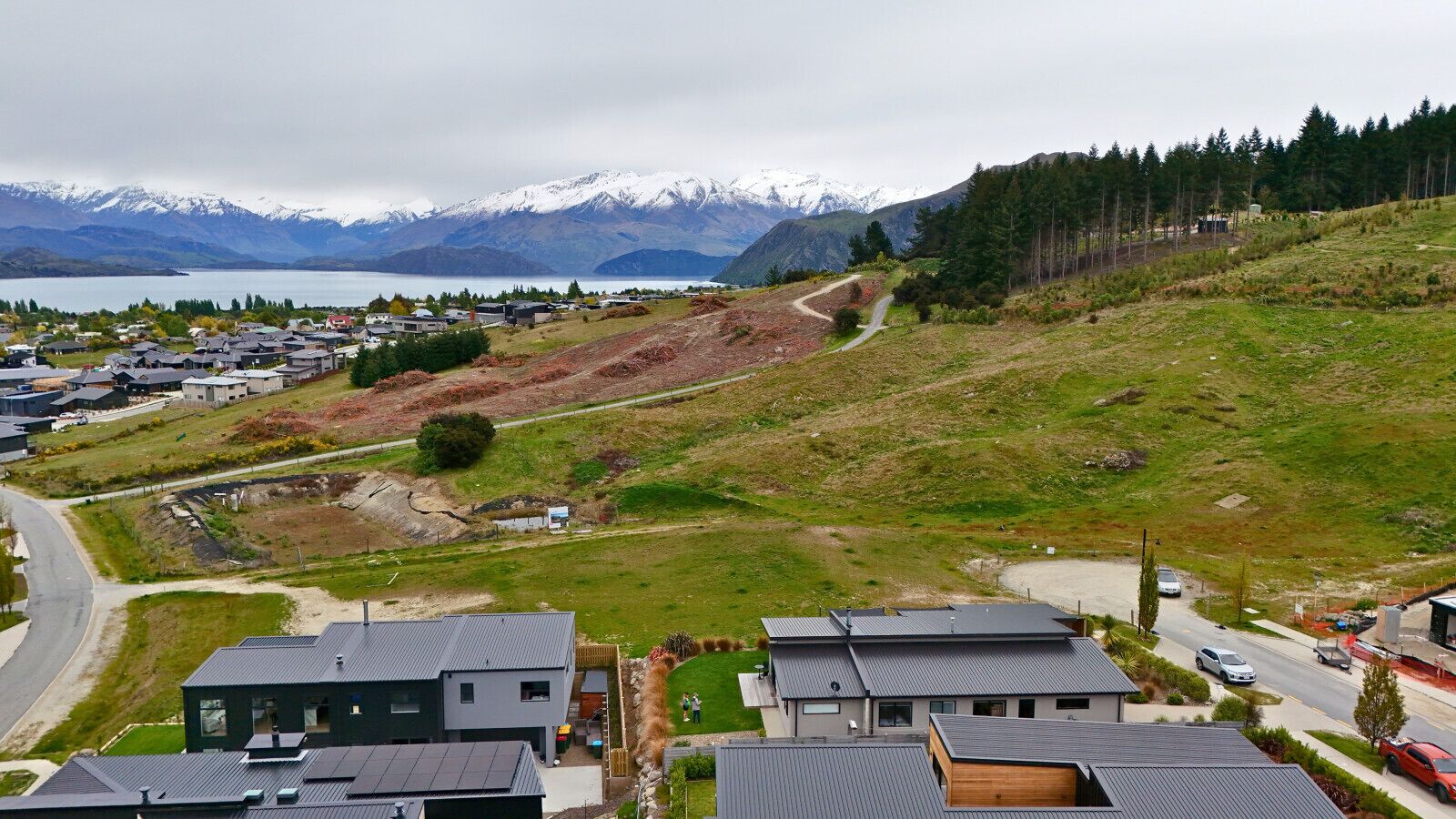 A residential area with modern houses, a winding road, and a mountainous backdrop.
