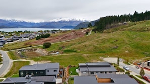 A residential area with modern houses, a winding road, and a mountainous backdrop. - Stunning Lake Wanaka Retreat (Wānaka)