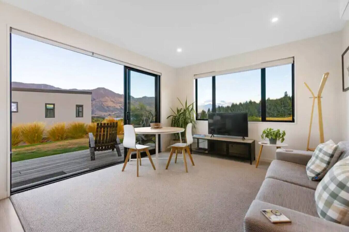 A modern living room with a large TV, a sofa, and a dining area with chairs.