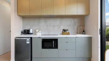 A compact kitchen with a refrigerator, microwave, and a coffee maker on the counter.