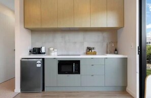 A compact kitchen with a refrigerator, microwave, and a coffee maker on the counter. - Stunning Lake Wanaka Retreat (Wānaka)
