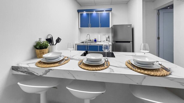 Una cocina moderna con encimera de mármol, armarios azules y un refrigerador de acero inoxidable.