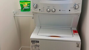 A front-loading washer and dryer in a laundry room with a shelf above holding a detergent bag. - Home away from home. Perfect place to relax (Riverview)