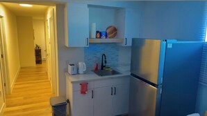 A compact kitchen with a stainless steel refrigerator, a sink, and white cabinets. - Home away from home. Perfect place to relax (Riverview)