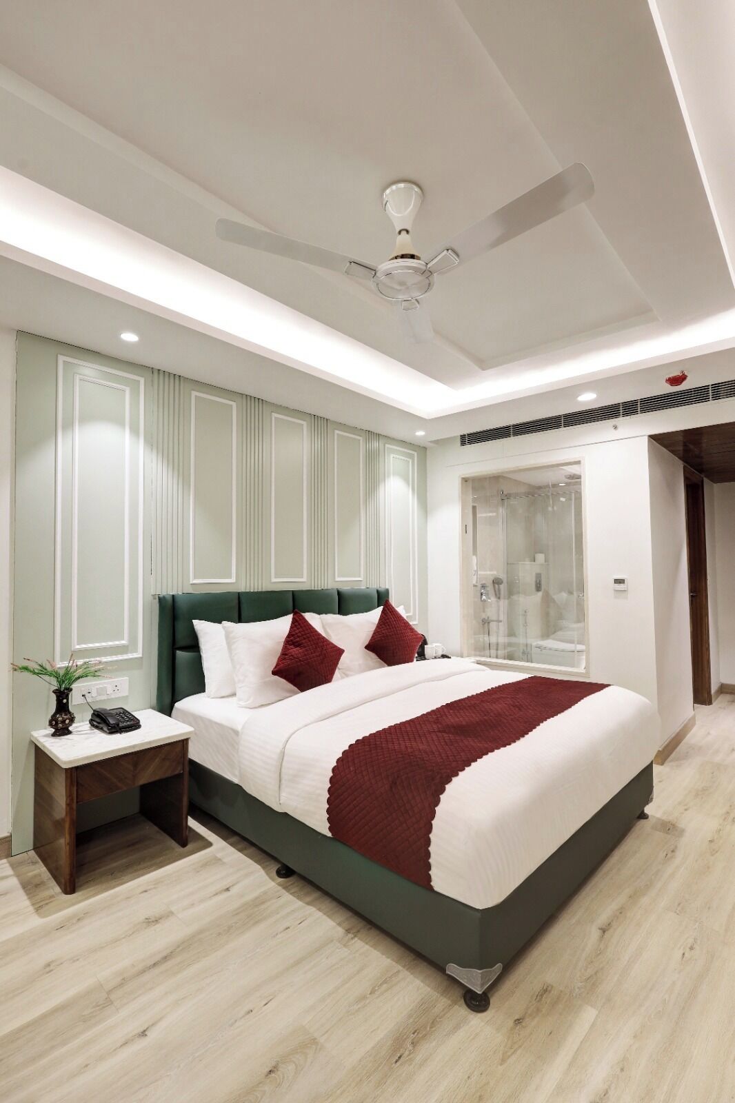 Quarto moderno com cama, mesa de cabeceira e ventoinha no teto.
