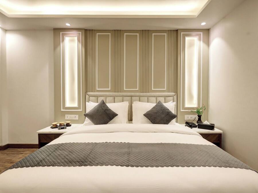 A modern hotel room with a large bed, two bedside tables, and a nightstand with a lamp.