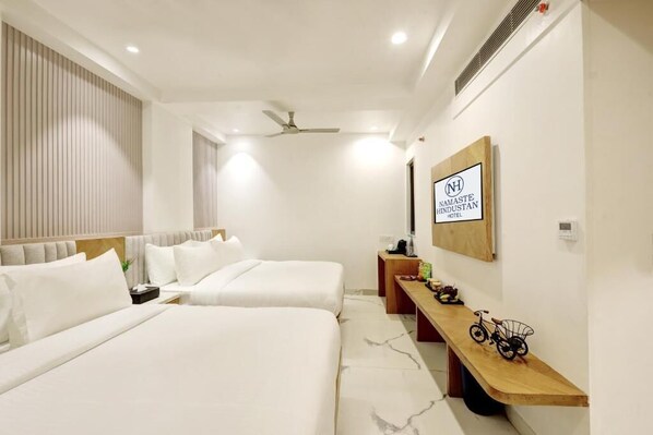A hotel room with two beds, a wooden bench, a bicycle, and a sign for Namaste Hindustan Hotel.
