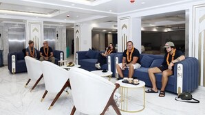 Een moderne lobby met blauwe banken, witte stoelen en een marmeren vloer.