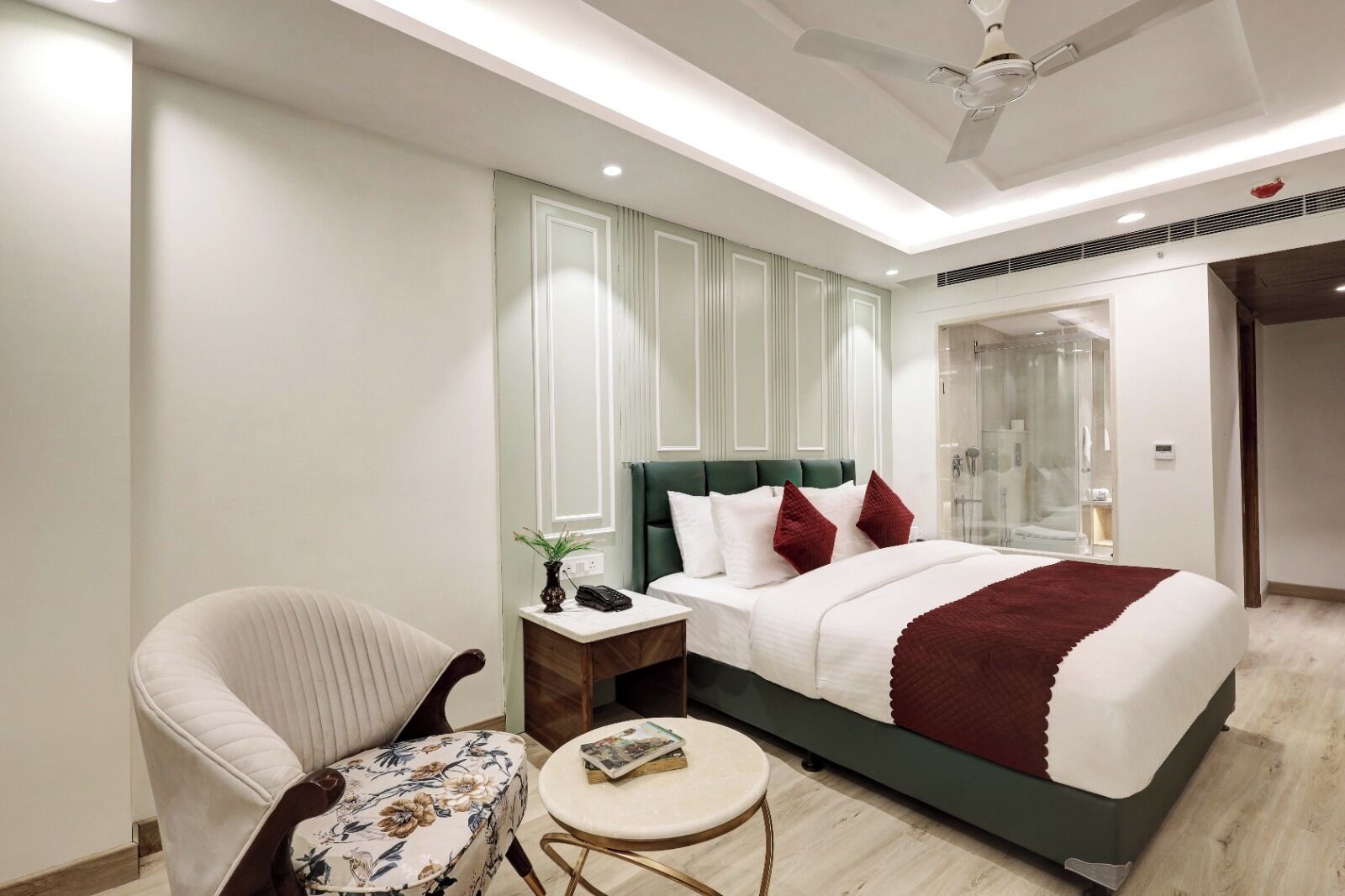 Una habitación de hotel moderna con una cama, una silla, una mesita y un ventilador de techo.