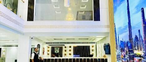 A lobby with a large chandelier, a reception desk, and a cityscape mural.