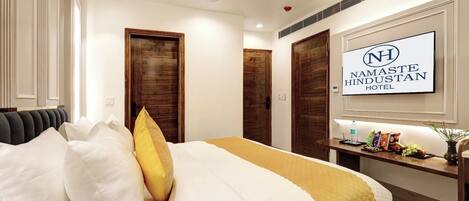 A hotel room with a bed, a bedside table with snacks, a TV, and a ceiling fan.