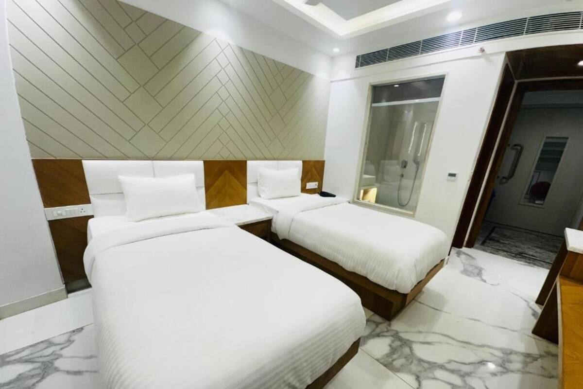Quarto de hotel com duas camas, chuveiro e piso de mármore.