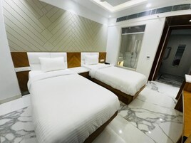 Habitación de hotel con dos camas, ducha y suelo de mármol.