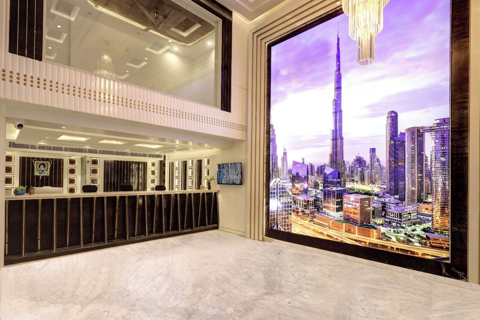A modern hotel lobby with a reception desk, a large digital cityscape display, and a marble floor.