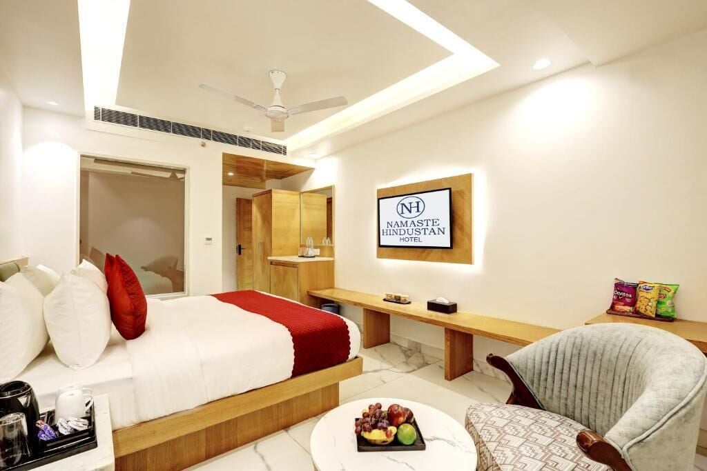 A modern hotel room with a bed, a desk, a chair, and a fruit tray.