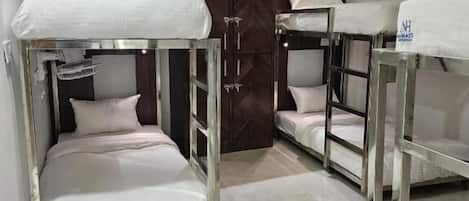 A hotel room with bunk beds, a wooden wardrobe, and a ceiling fan.
