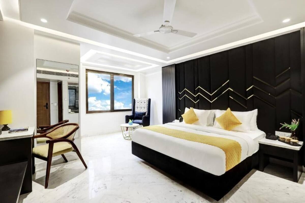 Quarto de hotel moderno com uma cama grande, uma mesa, uma cadeira e vista do céu.