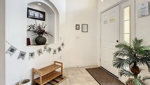 Ein sauberer, moderner Korridor mit einer Holzbank, einem Willkommensbanner, einem Topfpflanzen und einer Tür mit einem Schild.
