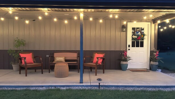 An outdoor patio with a covered seating area, string lights, and potted plants.