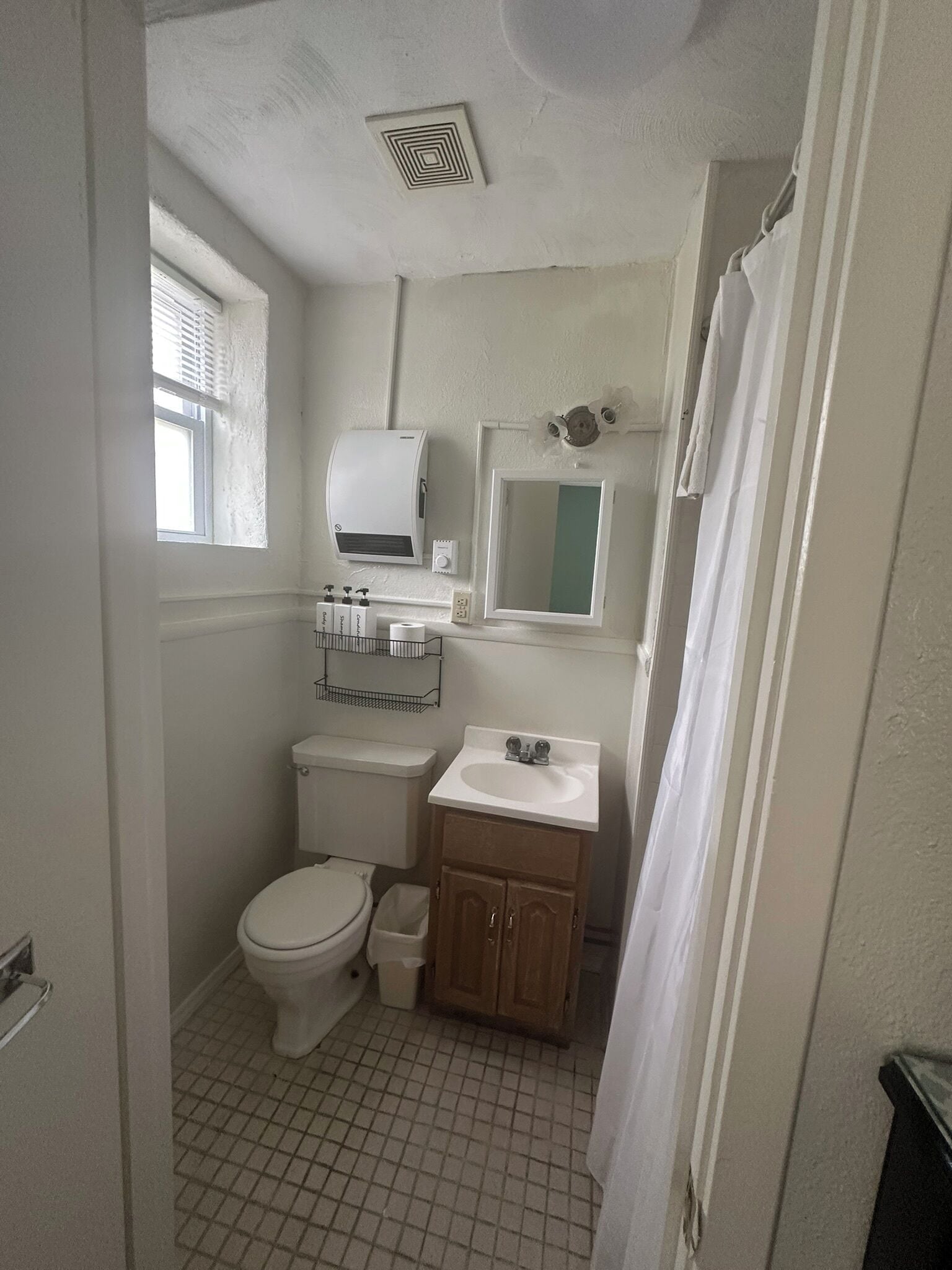 A small, compact bathroom with a toilet, sink, and window.