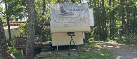 A recreational vehicle (RV) parked in a wooded area with a picnic table nearby.