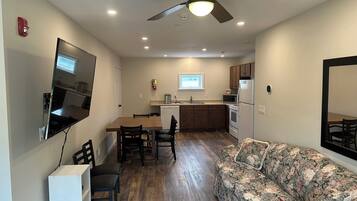 A compact living space with a dining area, kitchenette, and a sofa.