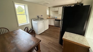 Una cocina compacta con lavadora, refrigerador y un comedor con mesa y sillas.