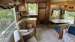 Cocina compacta para autocaravana con armarios de madera, un lavabo y una zona de comedor.