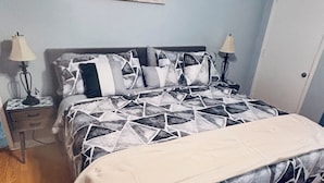Une chambre à coucher avec un lit, deux tables de chevet, un ventilateur de plafond et une porte.