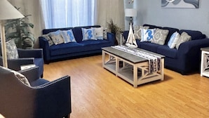 Un salon avec un canapé bleu, une table basse et un ventilateur de plafond.