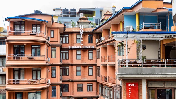 Ein mehrstöckiges Hotel mit Balkonen, einem Schild mit der Aufschrift "HOTEL THAMEL CENTER" und einem sichtbaren Eingang.