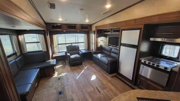 Un intérieur de camping-car compact comprenant un coin cuisine, un espace salon et de grandes fenêtres.