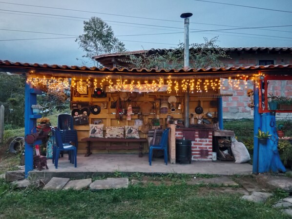 Un puesto rústico de mercado al aire libre con una variedad de artículos a la venta, incluyendo utensilios de cocina y objetos decorativos.