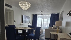 Un comedor con candelabro, televisor y sofá.