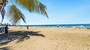Una playa con palmeras, sombrillas y gente.