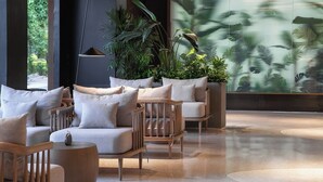A modern lobby with seating areas, large windows, and a tropical-themed mural. - YangShuo Percent Hotel (Guilin)