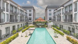 A modern hotel with a central swimming pool, multiple balconies, and a view of a distant building. - Soho Villa&Resort (Khemarak Phoumin)