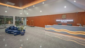 A modern reception area with a wooden ceiling, a reception desk, and a seating area with blue sofas. - Soho Villa&Resort (Khemarak Phoumin)