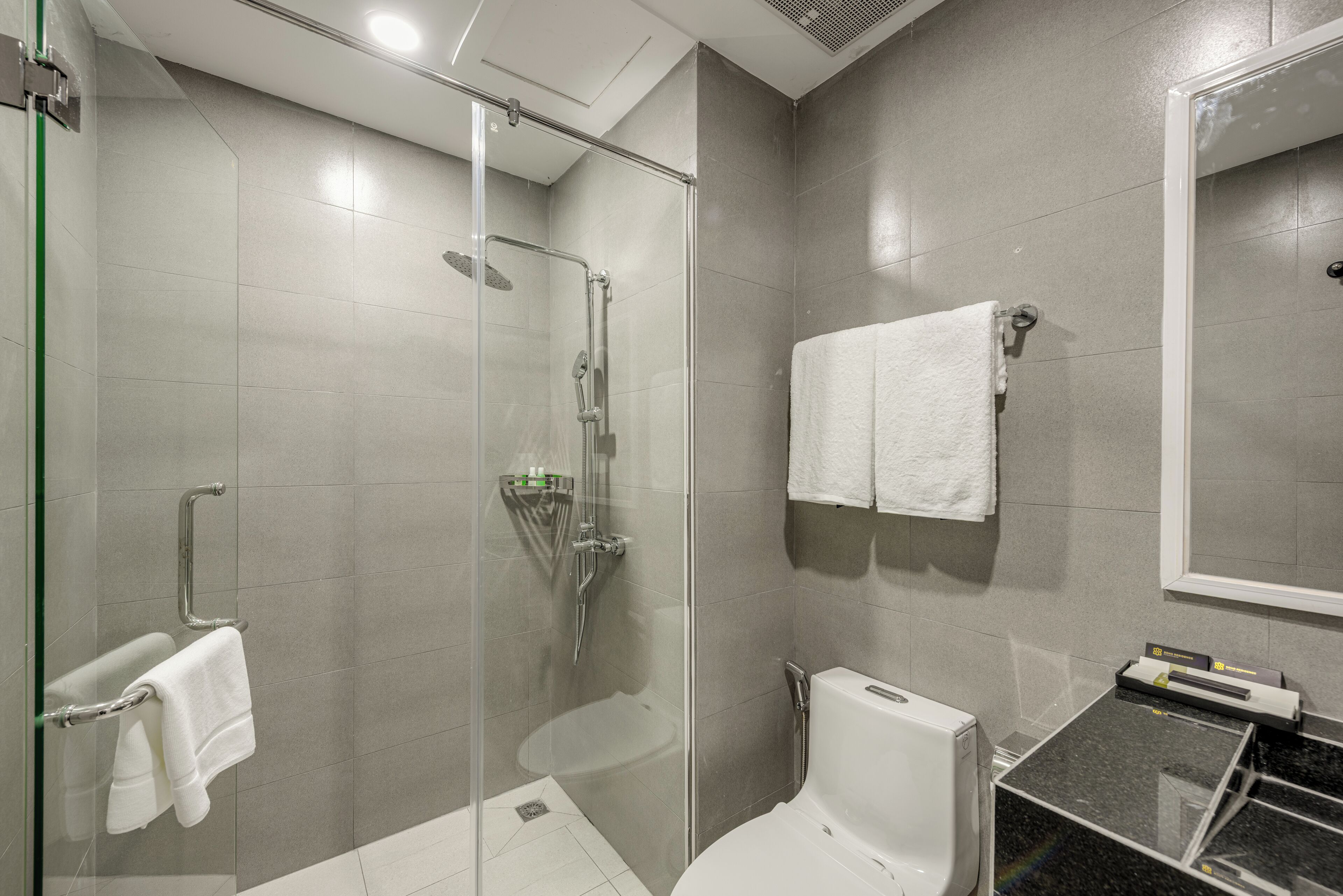 Un bagno moderno con doccia vetro, toilette e lavandino.