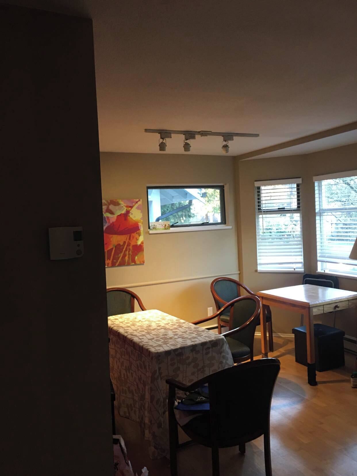 A dining area with a table and chairs, a window with blinds, and a ceiling light fixture.
