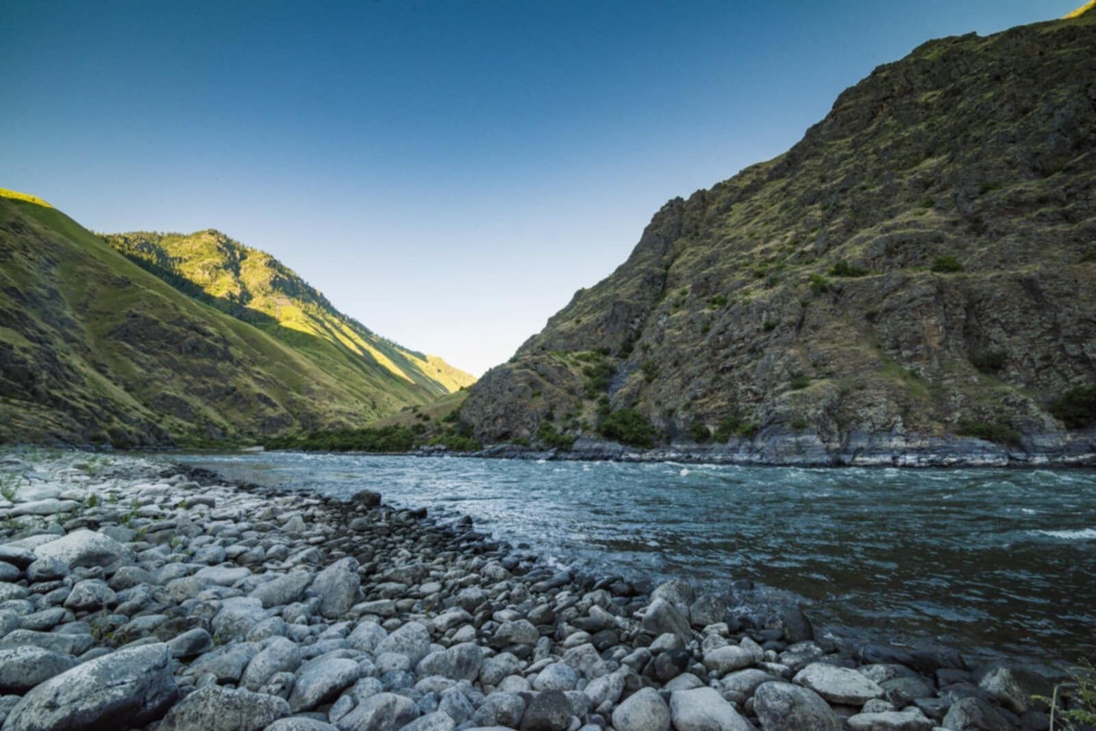 A river flowing through a rocky landscape with steep hills on either side.