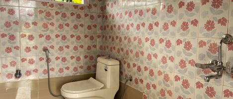 Un baño con inodoro, ducha y ventana.