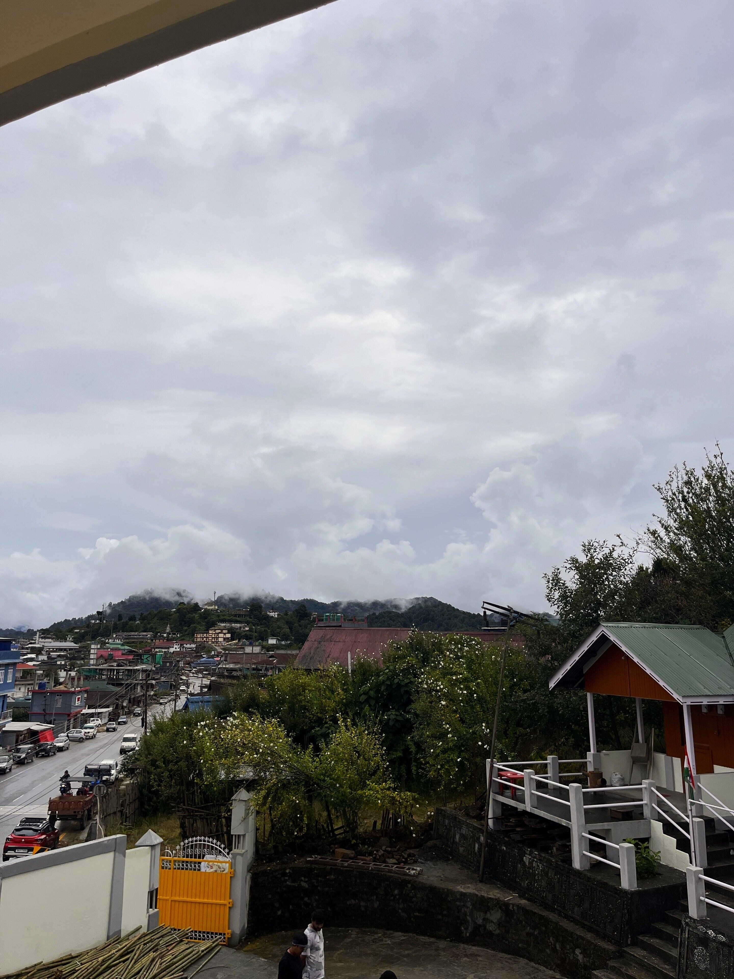 A residential area with a street, houses, and a hill in the background.