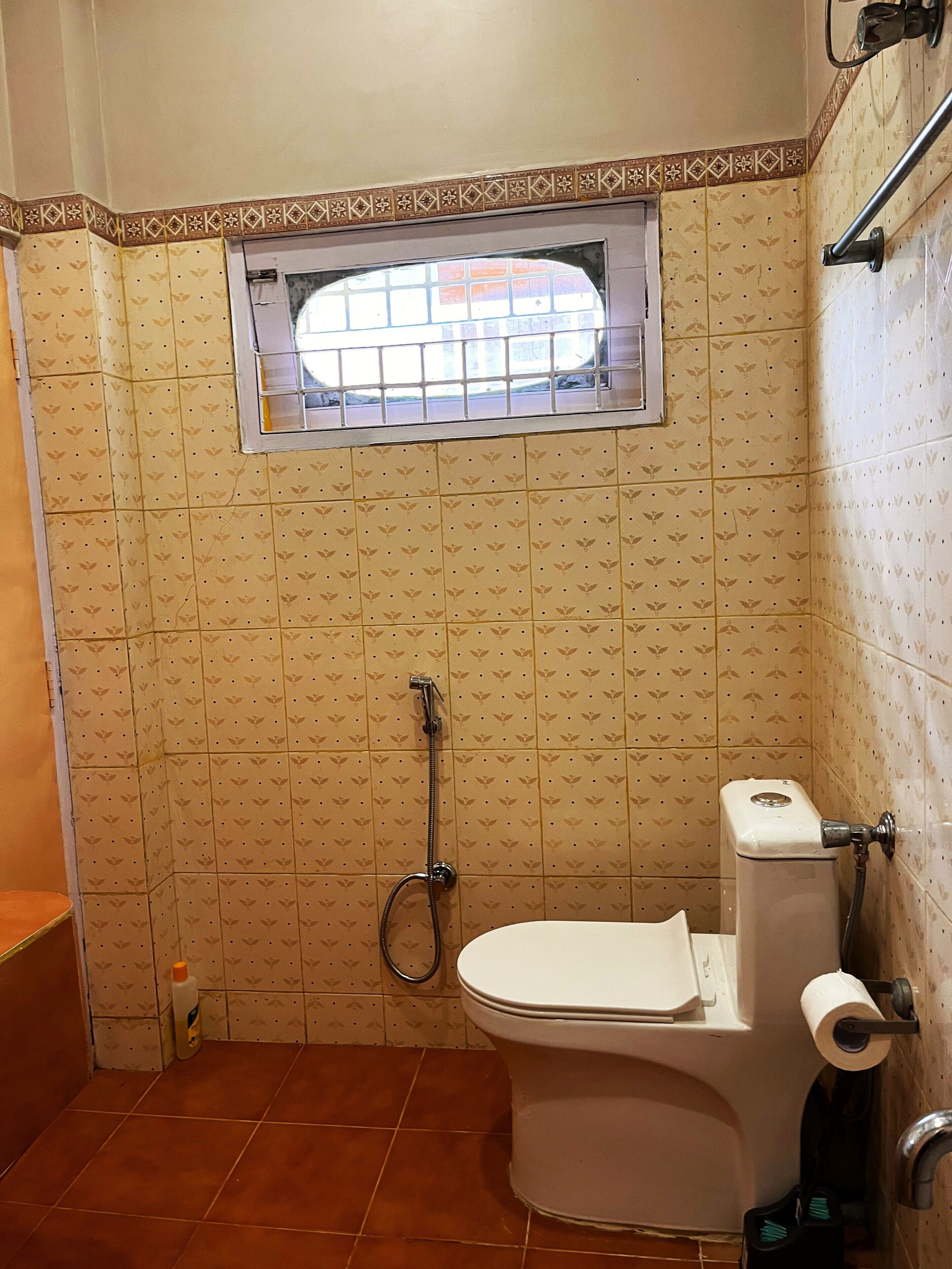 A bathroom with a toilet, a shower, and a window.
