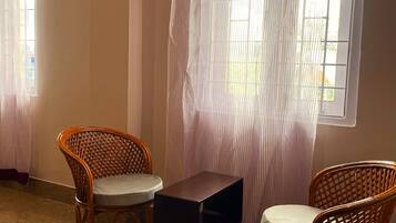 A room with two wicker chairs, a small table, and a window with striped curtains.