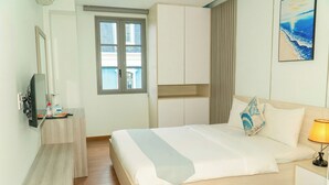 Ett hotellrum med en säng, en tv, ett fönster och en tavla.