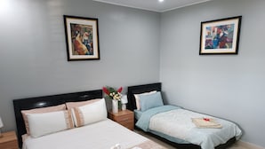 Habitació d'hotel amb dos llits, una tauleta de nit amb una làmpada i dos quadres emmarcats a les parets.