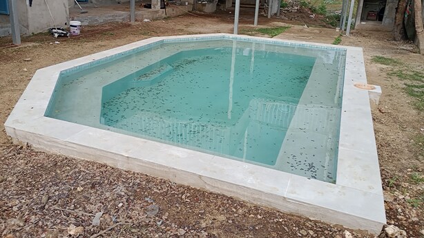 Una piscina rectangular amb vora enrajolada, envoltada per una zona de grava.
