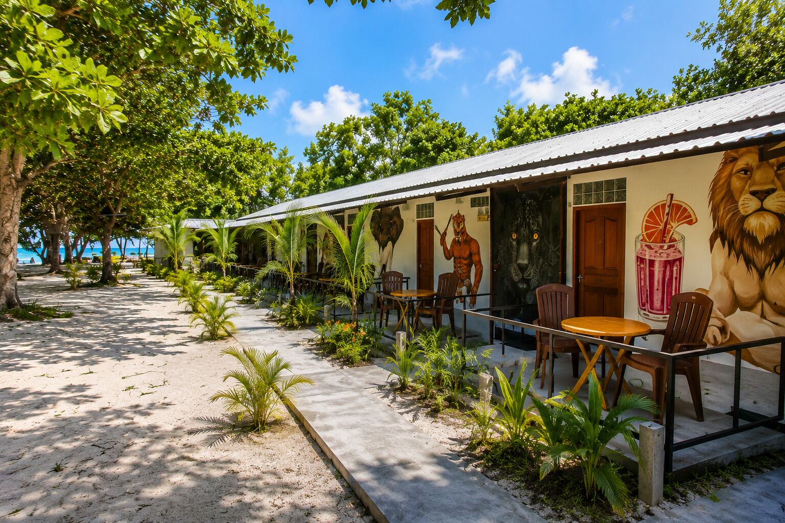 A beachfront building with outdoor seating, a mural of a lion, and a view of the ocean.