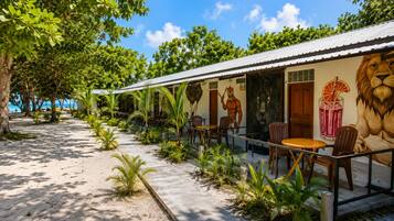 A beachfront building with outdoor seating, a mural of a lion, and a view of the ocean.